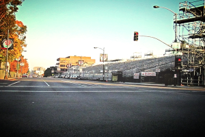Eine Straße mit einem Verkehrszeichenmast und Gerät auf der rechten Seite, Warnschilder und mehrere Fahrzeuge vor Bäumen auf der linken Seite.