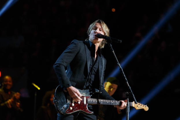 Keith Urban performs auf der Bühne im Joint in Las Vegas, spielt eine Gitarre mit einem Mikrofon vor ihm und Musikern im Hintergrund, unter dunkler Beleuchtung.