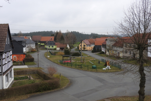 Kleinstädte mit Häusern, Straßeninfrastruktur, Fahrzeugen, Grünflächen, einem Spielplatz und einem klaren blauen Himmel.