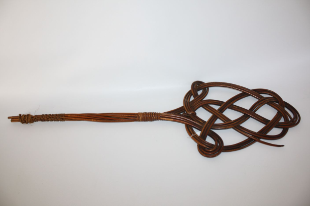 Eine braune Lederpeitsche mit einem Knoten darauf vor einem weißen Hintergrund.