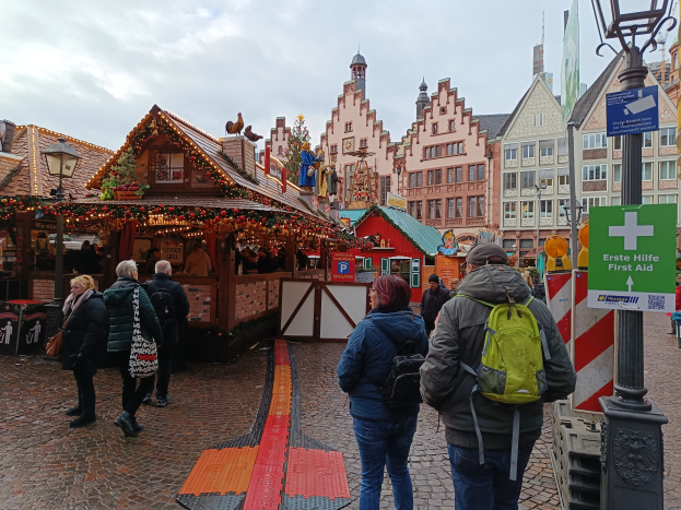 Eine Gruppe von Menschen geht eine Kopfsteinpflasterstraße in Nürnberg, Deutschland, entlang mit Laternenmasten, Texttafeln und Gebäuden mit Fenstern im Hintergrund unter einem bewölkten Himmel.