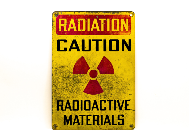 Gelbes Warnschild mit schwarzer Schrift "Strahlung Warnung" und einem radioaktiven Symbol auf einem weißen Hintergrund.