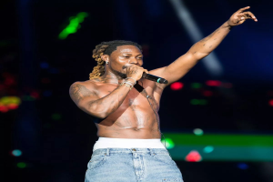 Travis Scott performs auf der Bühne beim Coachella Valley Music and Arts Festival, hält ein Mikrofon und ist von hellen Lichtern umgeben mit einem unscharfen, träumerischen Hintergrund.