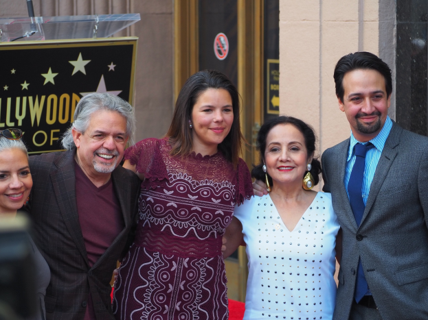 Gruppe von Menschen auf einem roten Teppich bei der Zeremonie der Hollywood Walk of Fame, die für ein Foto posieren und lächeln.