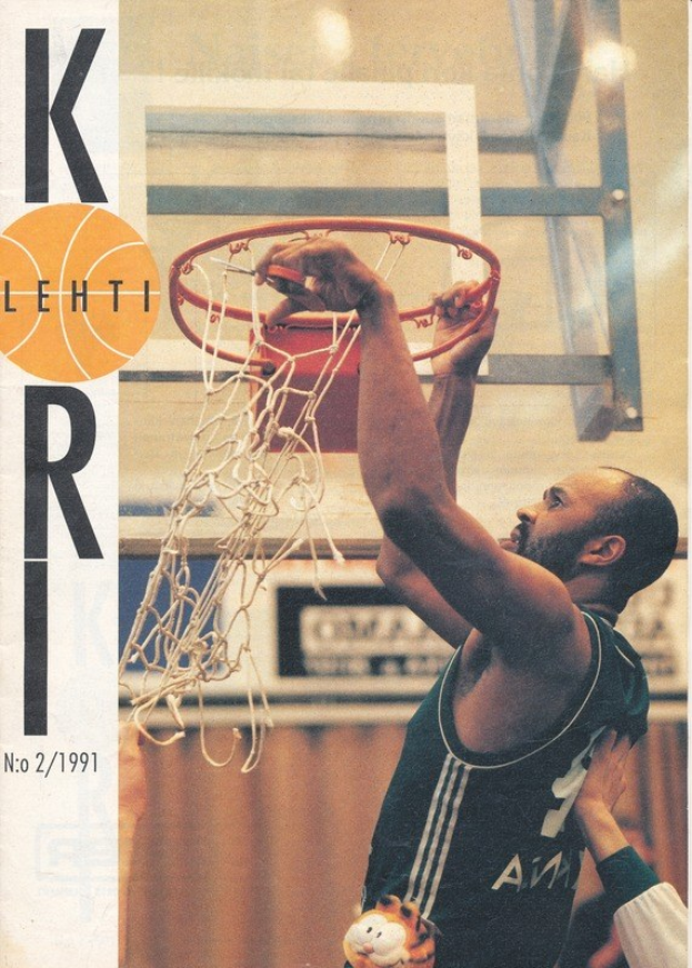 Ein Mann wirft einen Basketball in den Korb mit einem Basketballnetz im Hintergrund, während eine andere Person in der Nähe steht und eine Wand dahinter zu sehen ist. Text auf der linken Seite lautet "Kobe Bryant 1991-92 Basketball Card."
