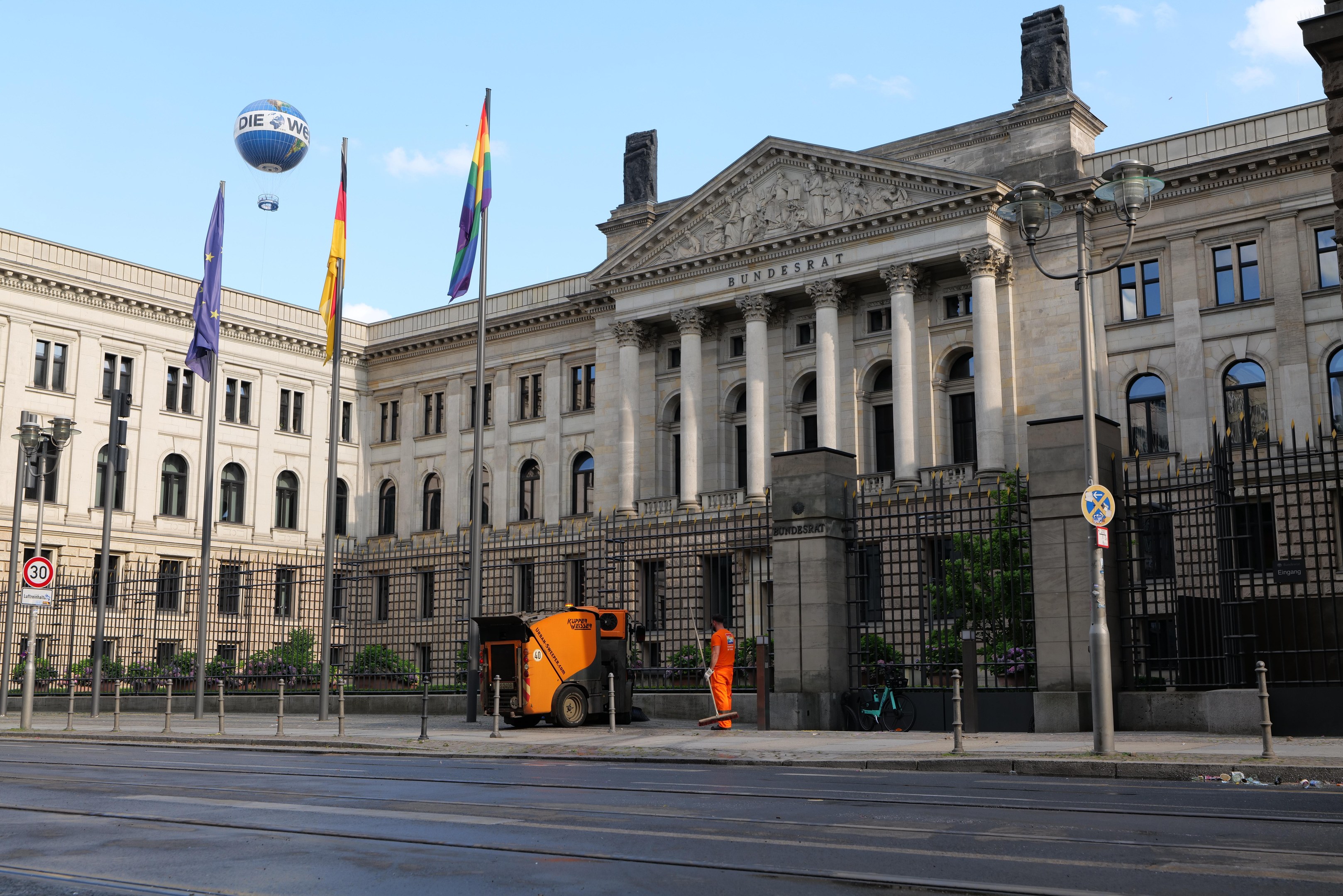 Großes modernes Gebäude mit vielen Fenstern, als der Bundestag in Berlin, Deutschland identifiziert, umgeben von Straßeninfrastruktur, Fußgängern und Bäumen unter einem bewölkten Himmel.