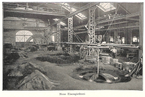 Ein altes Schwarz-Wei├č-Foto einer Fabrik mit Arbeitern, die eine Maschine bedienen, umgeben von Metallstangen und -pfosten, mit dem Text "Neue Eisenglebeerei, die erste Fabrik in Deutschland" unten.