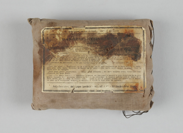 Kleiner Verbandkasten mit einer Papierzettel oben drauf.