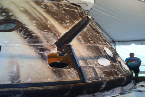 Eine Person steht unter einem Zelt vor einem Gegenstand.