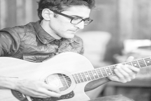 Ein Mann in einer Jacke spielt eine Gitarre.