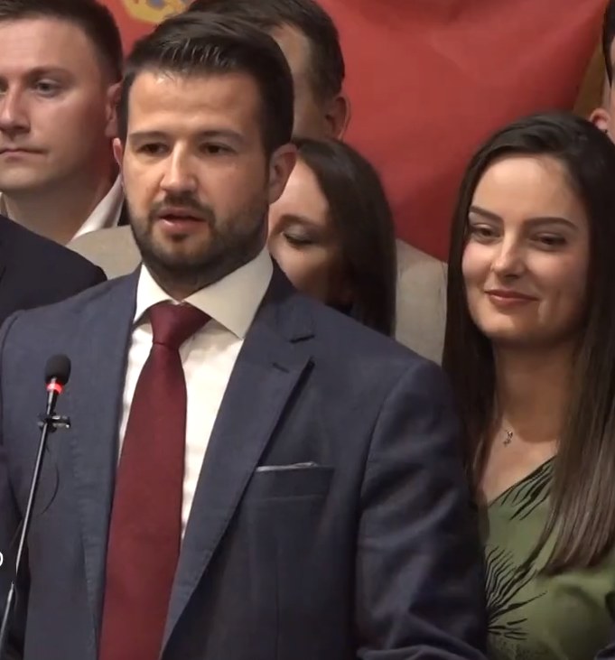 Ein Mann im Anzug spricht an einem Rednerpult mit einem Mikrofon zu einer Menge hinter einem Banner, wahrscheinlich über ein Verbot der sozialen Medien durch die Regierung.