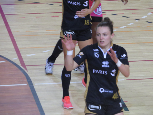 Eine Gruppe von Frauen in Sportkleidung und -schuhen spielt Volleyball auf einem Platz.