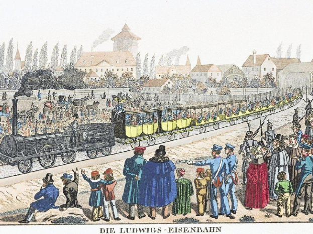 Eine Gruppe von Menschen um ein Zug auf einem Gleis herumstehend, mit einigen im Zug und anderen auf dem Boden, vor Gebäuden und Bäumen, mit Text 'Ludwigs-Eisenbahn, der erste Bahnhof in Deutschland' unten.