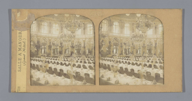 Ein altes Foto eines prächtigen Hotelballsaals mit Tischen, Stühlen, Kronleuchtern und Fenstern, das den Text "Sale à Manger, Grand Hotel" links zeigt.