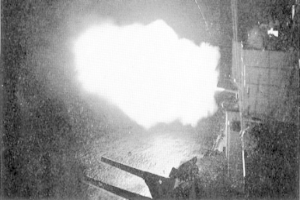 Ein Schwarz-Weiß-Foto einer großen Explosion in einem dunklen Raum, mit Rauch, der herausquillt, einer Stange und einer Wand auf der rechten Seite und Text unten.