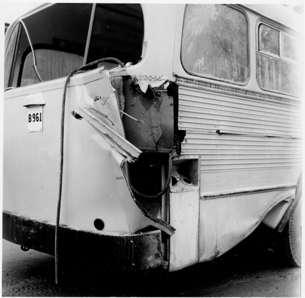 Schwarz-weißes Foto eines Busses mit schwerer Frontschaden durch einen Autounfall auf der Straße.