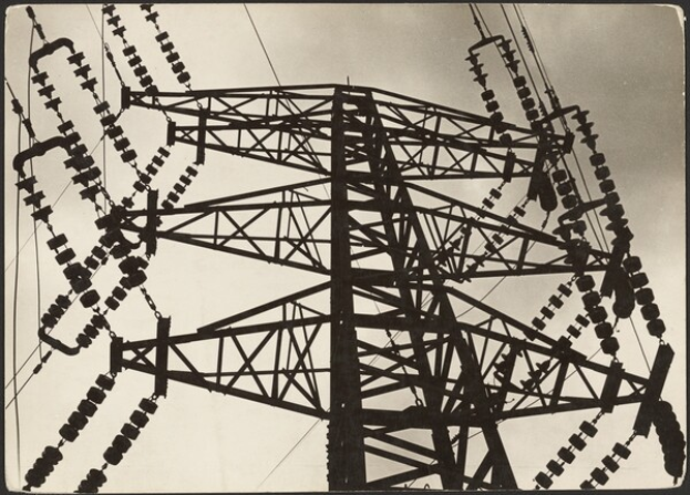 Ein Schwarz-Weiß-Foto einer Hochspannungsleitung mit einem Masten und Drähten im Vordergrund und einem Himmel im Hintergrund, mit Text am unteren Rand des Bildes.