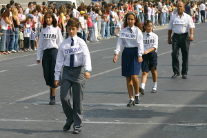 Eine Gruppe von Menschen, die auf einer Straße gehen, mit Abzeichen auf ihren Hemden, umgeben von einer großen Menge.