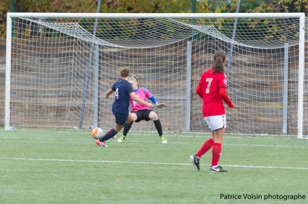 Gruppe von Frauen, die Fußball auf einem Rasenfeld mit Bäumen im Hintergrund und einem Torpfosten spielen, mit Text unten.