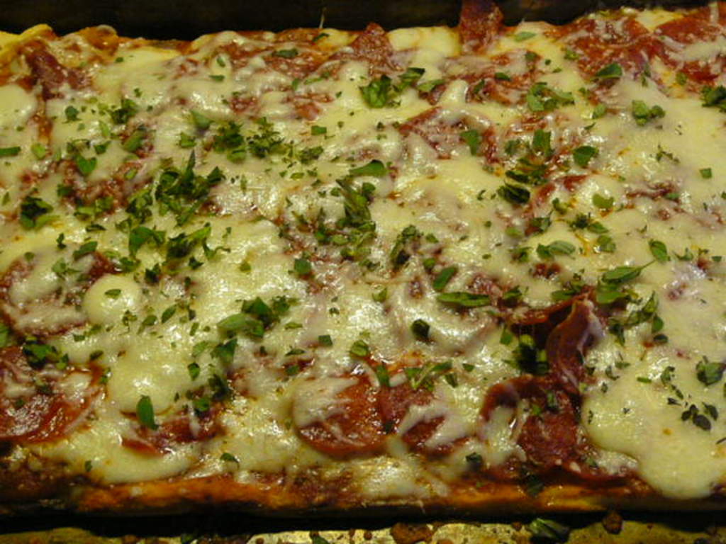 Ein Lebensmittel, das mit Käse garniert ist, auf einem Tablett.