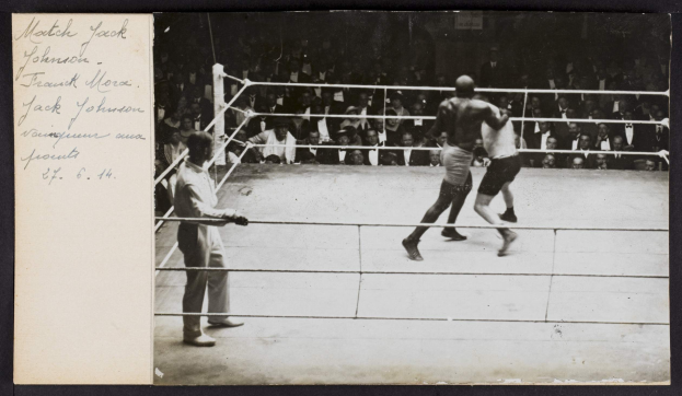 Schwarz-weiß-Foto von zwei Boxern im Ring mit einem Schiedsrichter und Zuschauern, beschriftet mit "Jack Johnson vs Frank Morgan" in der oberen linken Ecke.