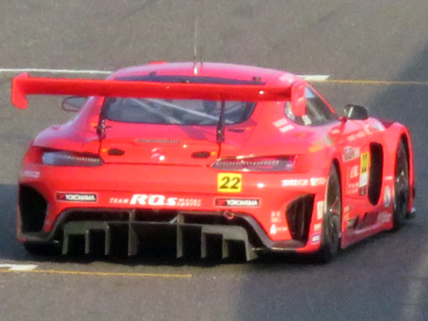 Ein leuchtend roter Porsche 911 GTS Rennwagen mit einer großen Heckspoiler und Flügel, der auf einer Rennstrecke fährt.