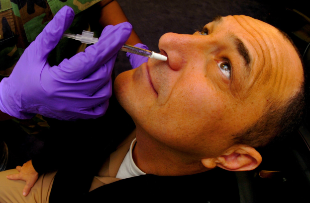 Ein Arzt in lila Handschuhen spritzt einem Mann ein Vakzin mit einer Spritze in den Mund.