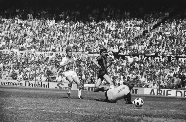 Schwarz-weißes Foto von Männern, die auf einem Feld Fußball spielen, mit Zuschauern im Hintergrund und einem Banner mit der Aufschrift "Bundesliga 1978-79 Ajax 1-1 Hannover 96."